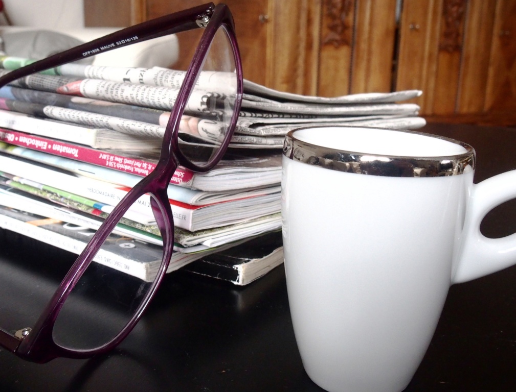 pile of magazines and newspapers with reading glasses and a cup of coffee to illustrate blackurrant press releases