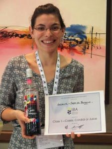 young lady holding a bottle of Vedrenne Creme de cassis Nouvelle Recolte and the award of the blackcurrant contest 2016