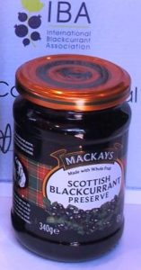 glass of Mackays Scottish blackcurrant preserve with the award of the blackcurrant contest 2016 in the background