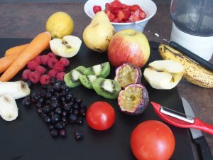 blackcurrants and several other fruits and vegetables with knife and blender for the preparation of smoothies