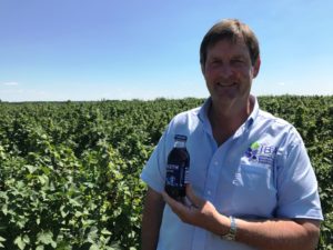 Anthony Snell, IBA president, standing in a blackcurrant field holding a bottle of Polish blackcurrant juice