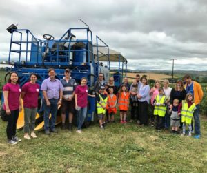 Group of people standing in front of a New Holland blackcurrant harvester at the Ribena Open Day in July 2017 at Windmill Hill, Herefeord