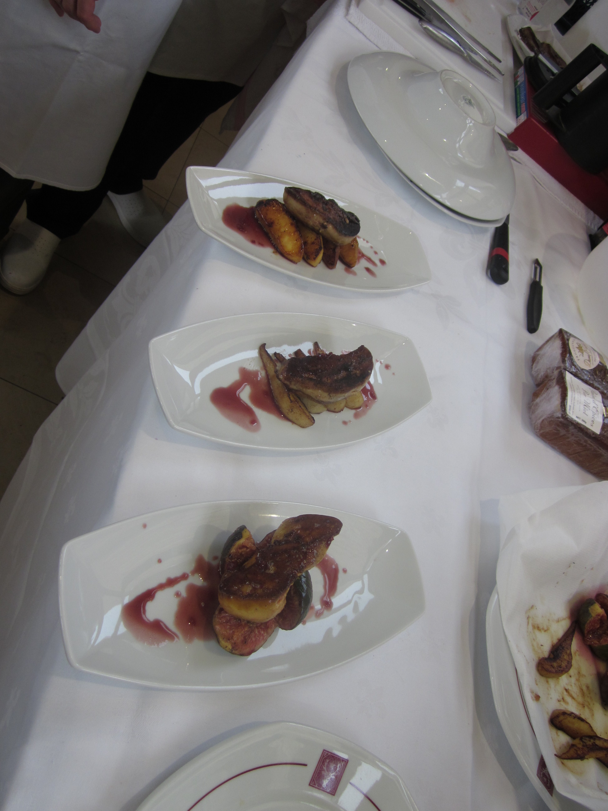 several plates with a piece of fried duck liver with cassis sauce around it
