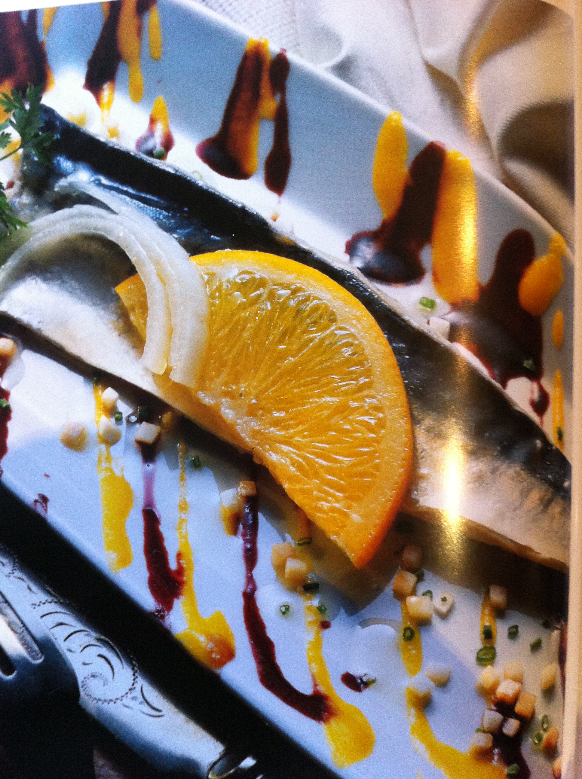 plate of mackerels with blackcurrant coulis and mandarin coulis, decorated with half a slice of orange