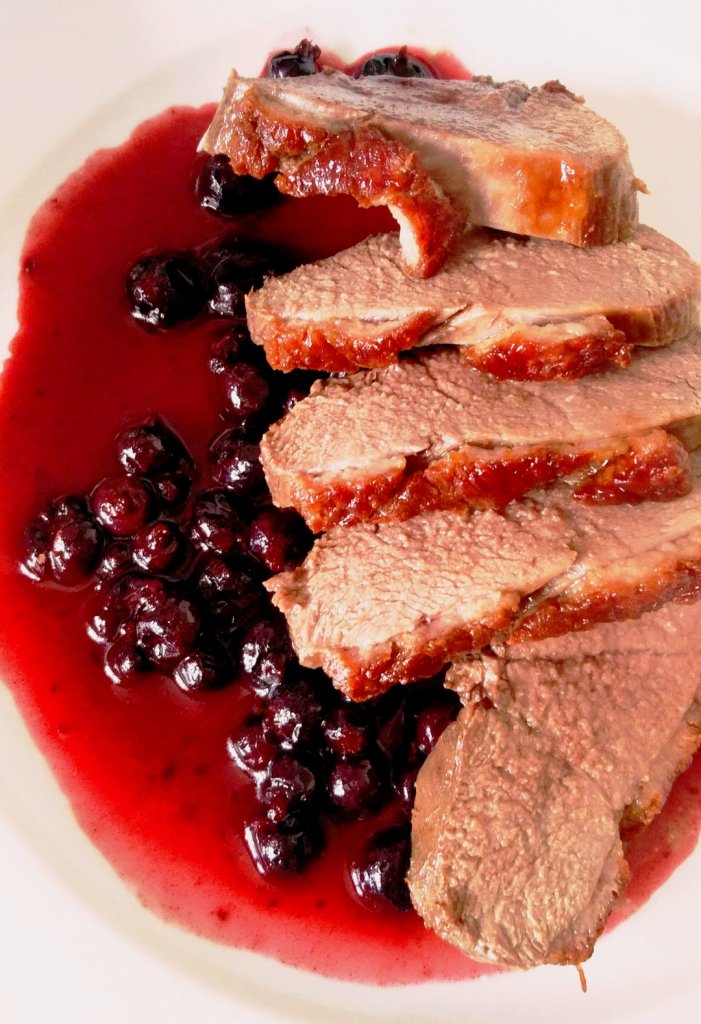 slices of duck fillet lying on a sauce blackurrants