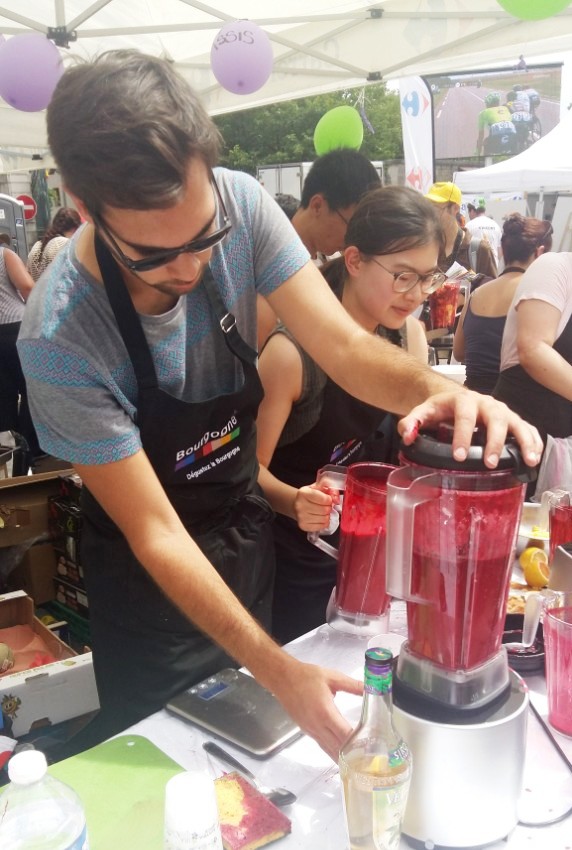 Young man preparing a vegan blackcurrant smoothie with a high speed blender