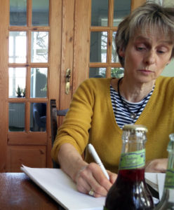 Annemarie Bisgaard, sitting at a table and writing