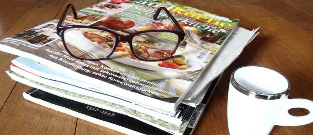 picture of magazines, a cup of coffee and reading glasses as a logo of the newsletter of the International Blackcurrant Association