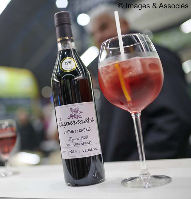 glass of blackcurrant spritz standing beside a bottle of Supercassis