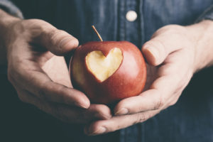 hands with apple, decorated with a heart, to illustrate engagement in sustainability